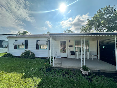 A tidy white single-story home with striped awnings and a covered porch, bought by Hidden Gems