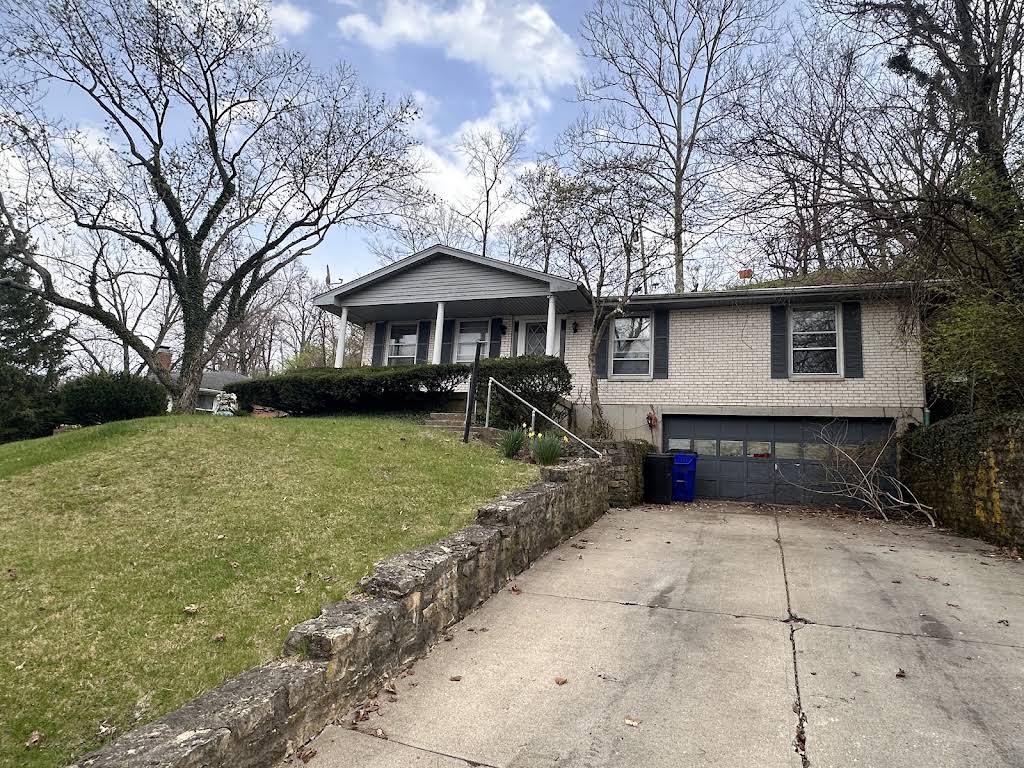 A brick and vinyl split-level home with a sloped front lawn — the kind of property Hidden Gems buys for cash